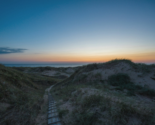 Spång till stranden i solnedgång i Frösakull